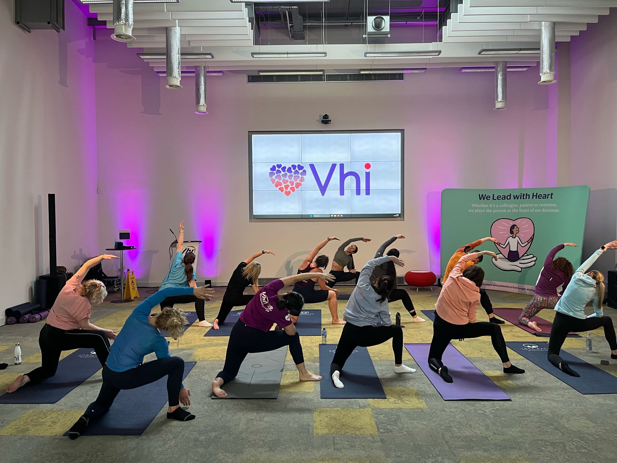 Group of colleagues doing a yoga stretch pose together in a corporate fitness class
