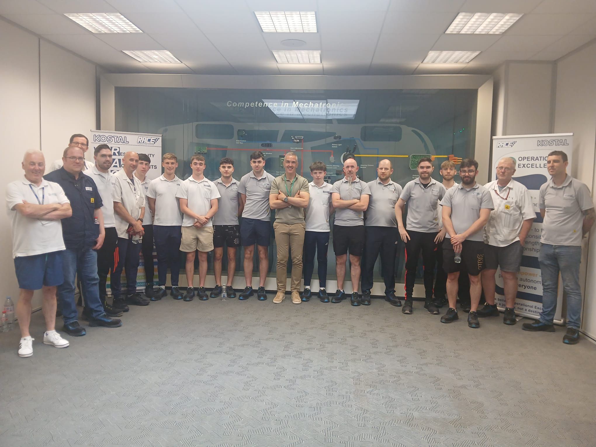 A group of male engineers and apprentices posing together in a workplace mechatronics training room
