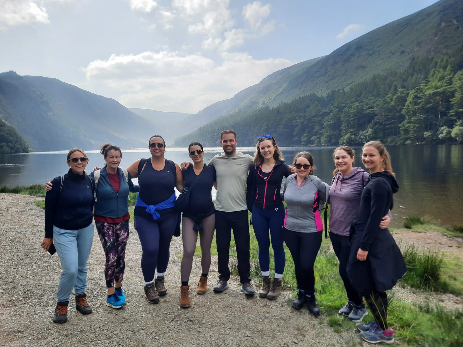Group of colleagues smiling together on a guided hike beside a lake in the mountains