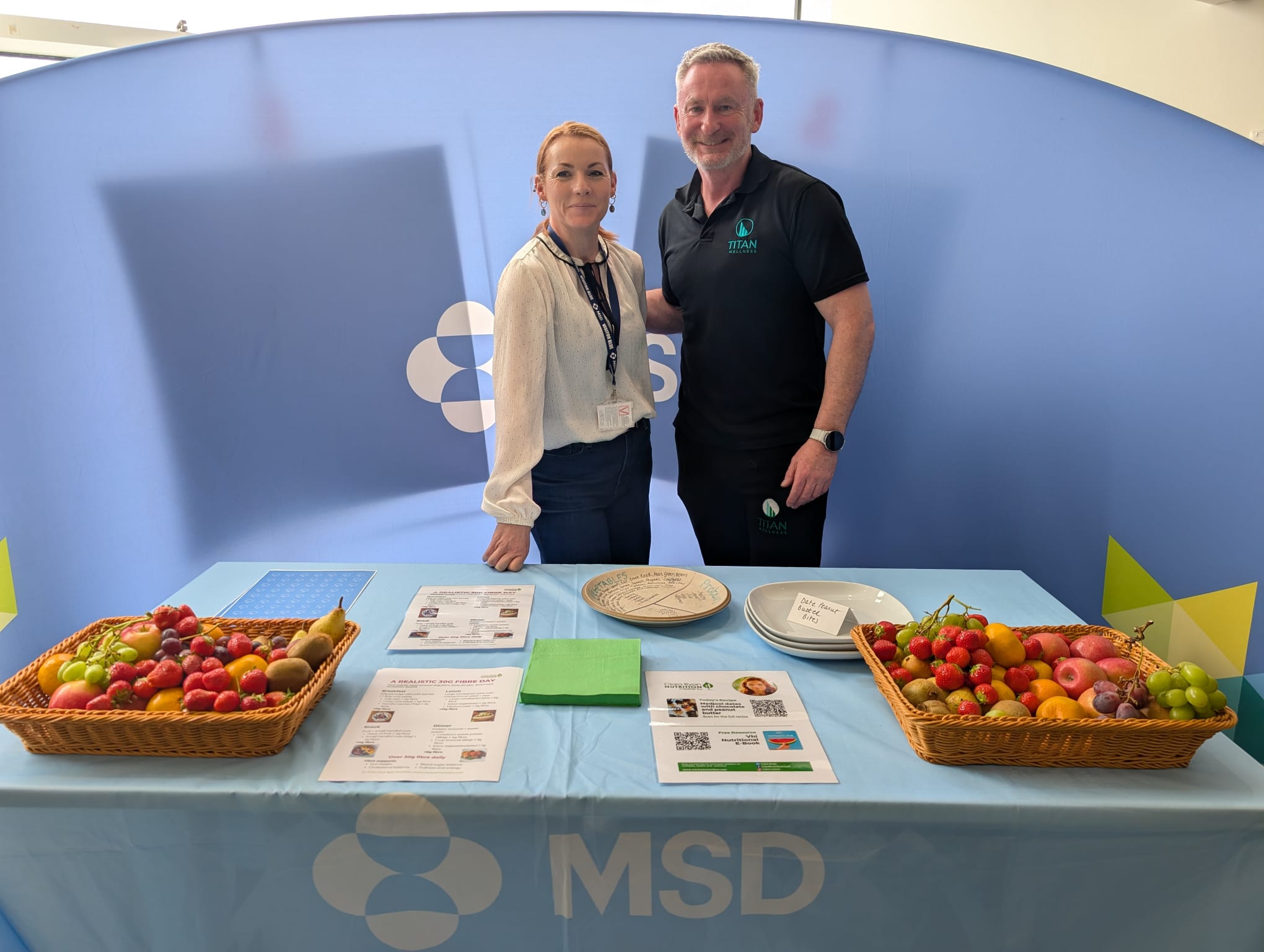 Titan Wellness nutrition stand with fruit baskets and fibre-guide handouts at a corporate wellbeing event